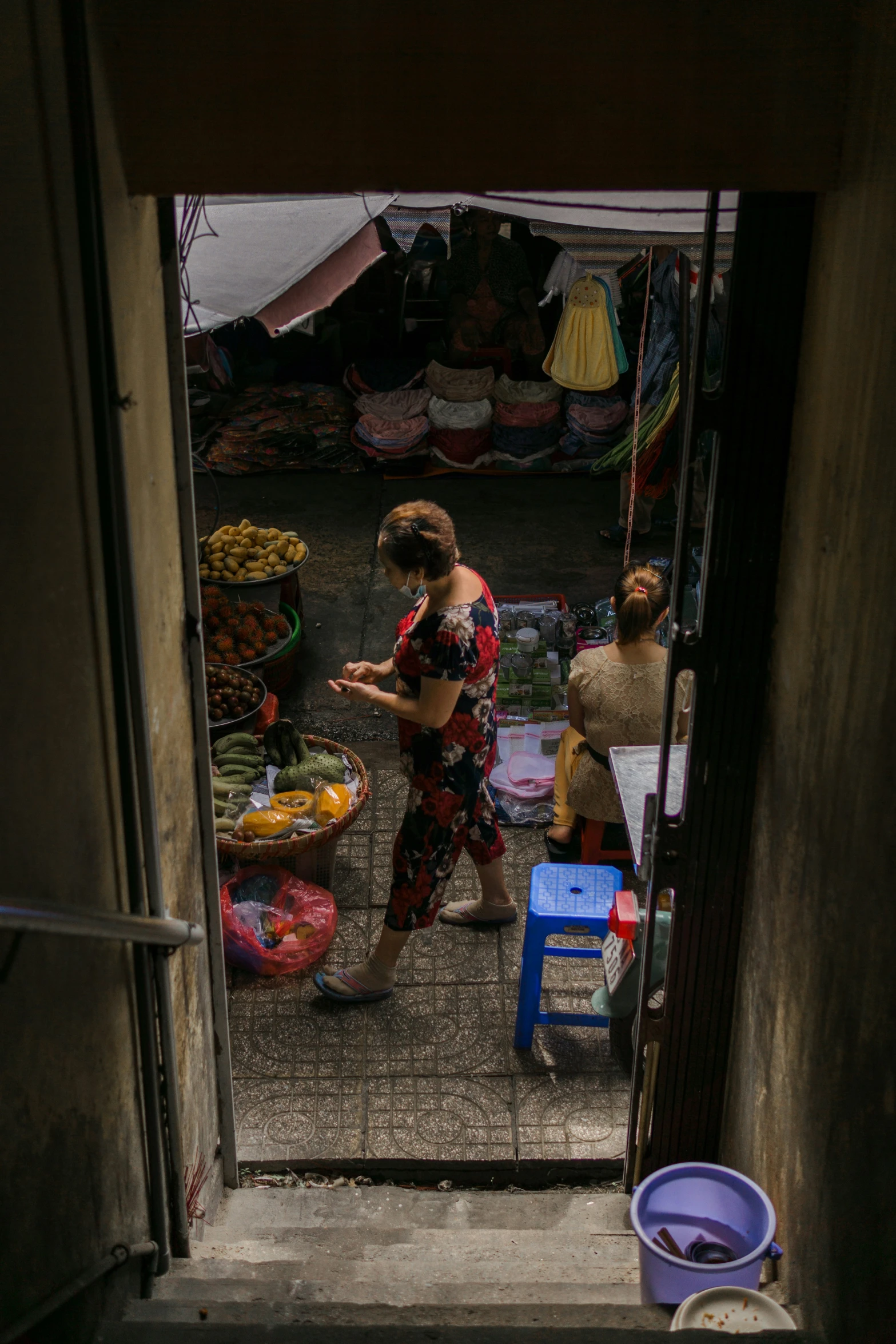 a woman walking down a dark alley in a market