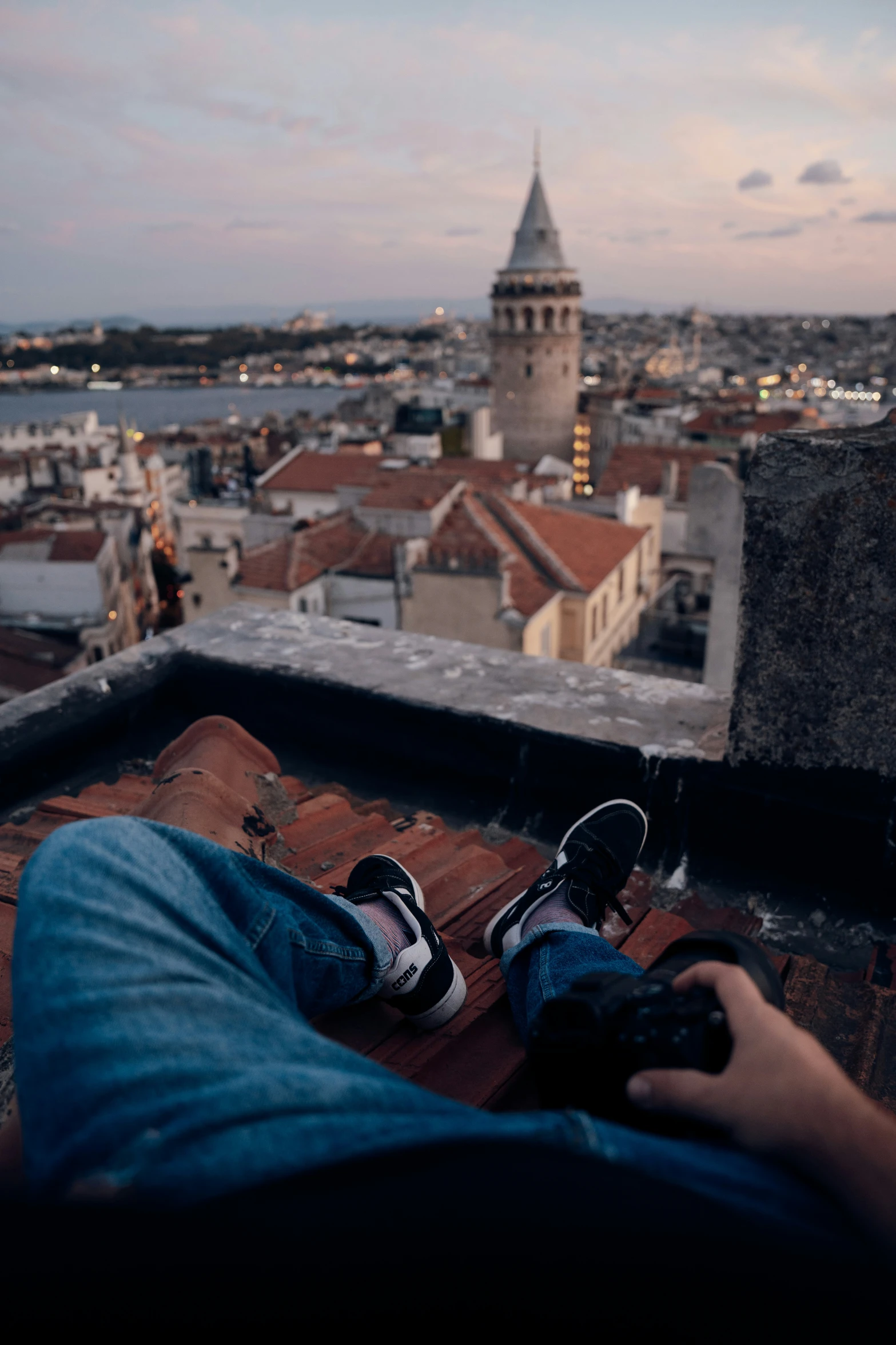 a person wearing flip flops and denim jeans, sitting on top of a roof