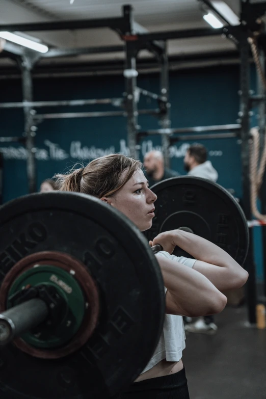 a female in a white shirt is doing some exercise with weights