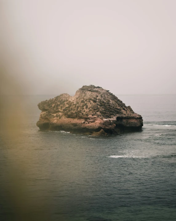 a rock outcropping in the ocean on a hazy day