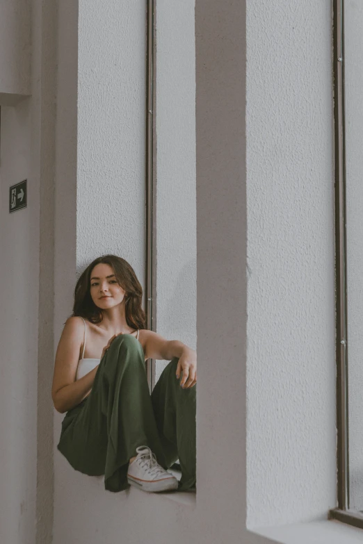 a girl in green pants is sitting on the wall