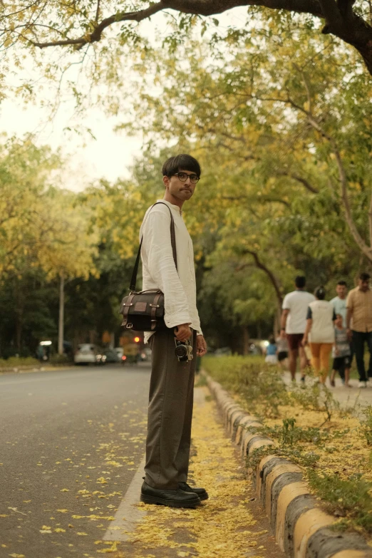 a man in white shirt and tie standing on side of road