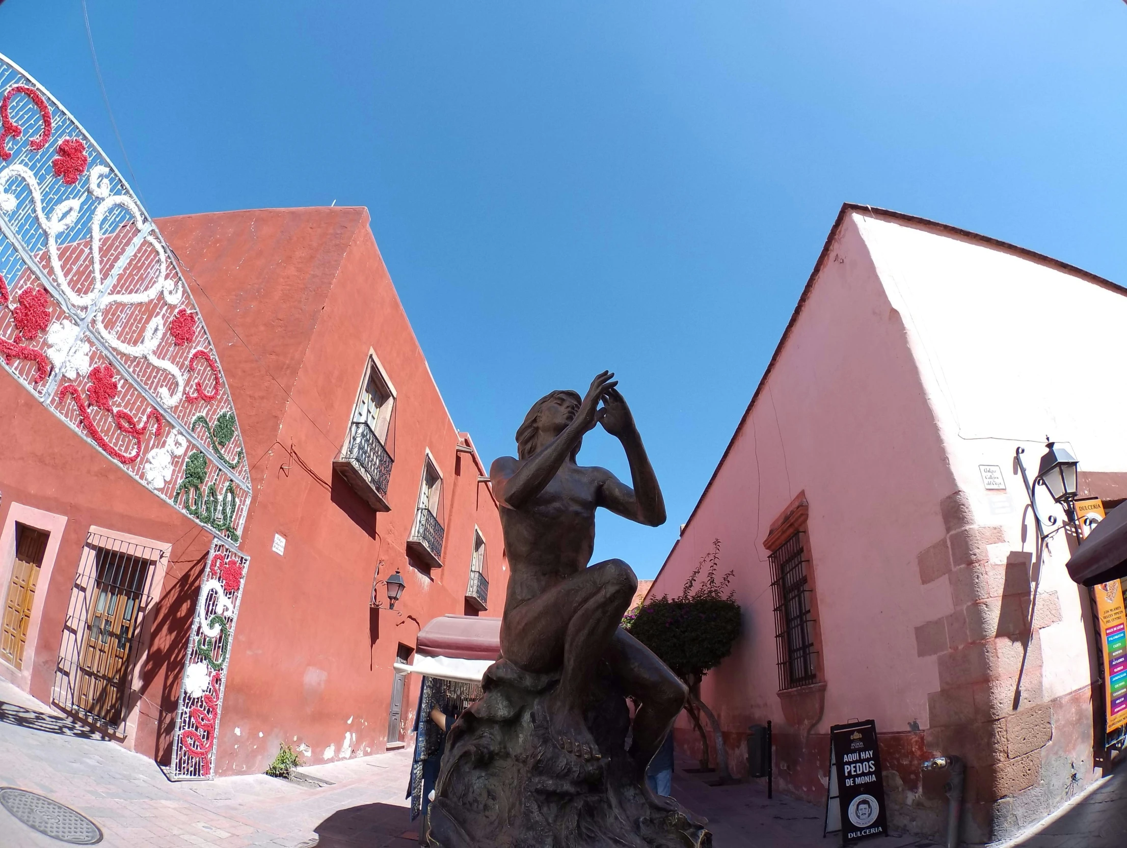 there is a statue in the street near many pink buildings