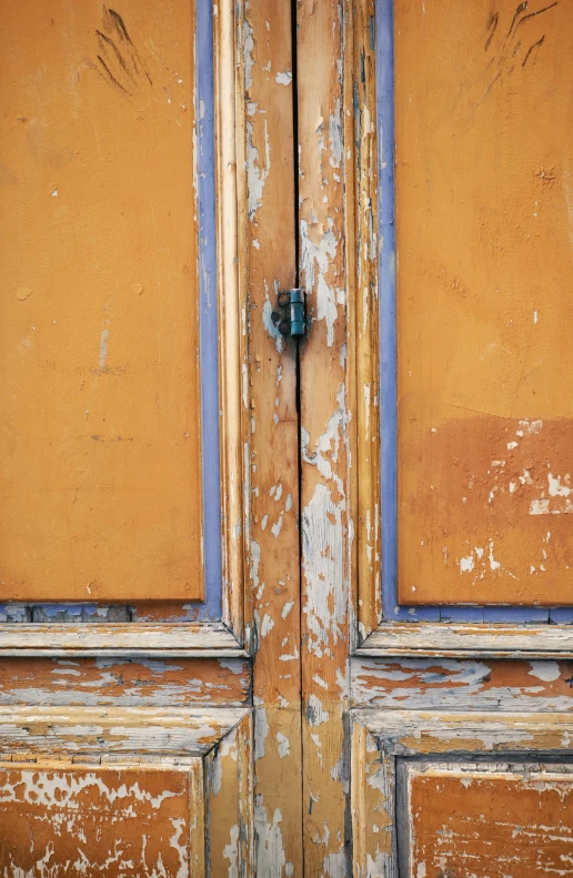 the wood door with peeling paint and blue trim is seen