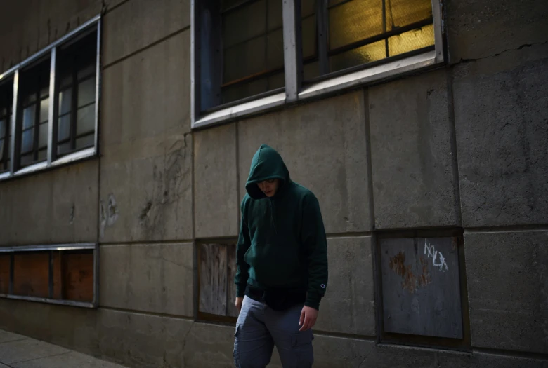 a man wearing a green hoodie is walking down the street