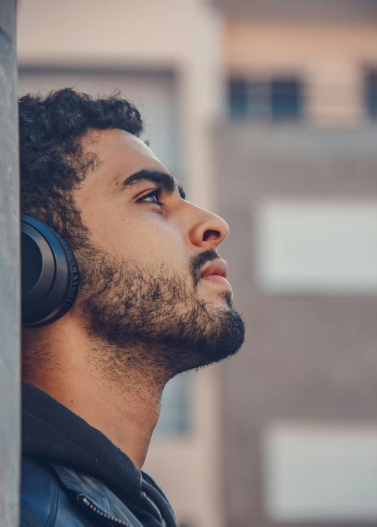 a man with earbuds standing next to a pillar