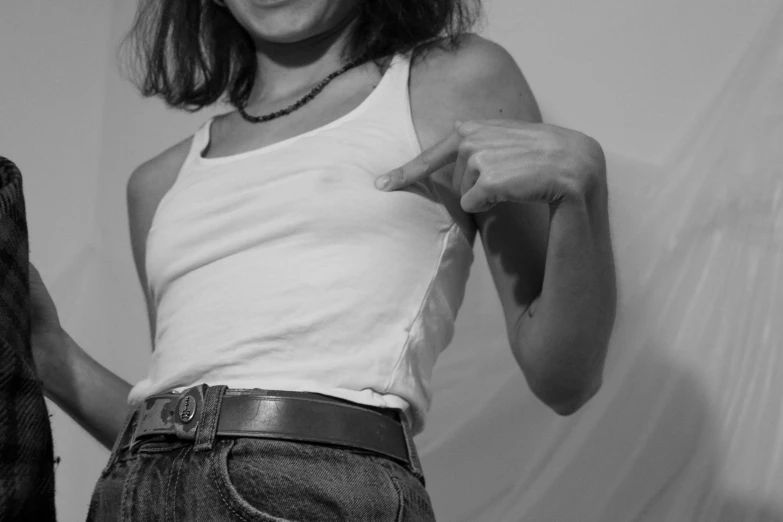 a woman wearing an unoned tank top holds her hair back