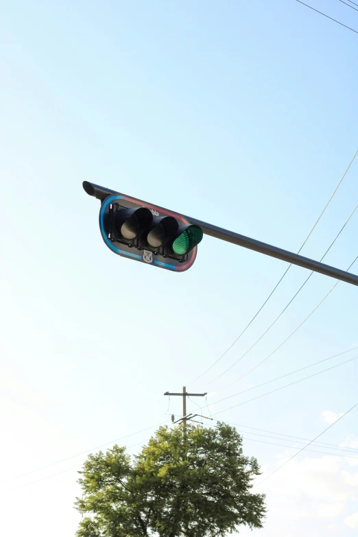 a traffic signal sitting above the street next to a tree