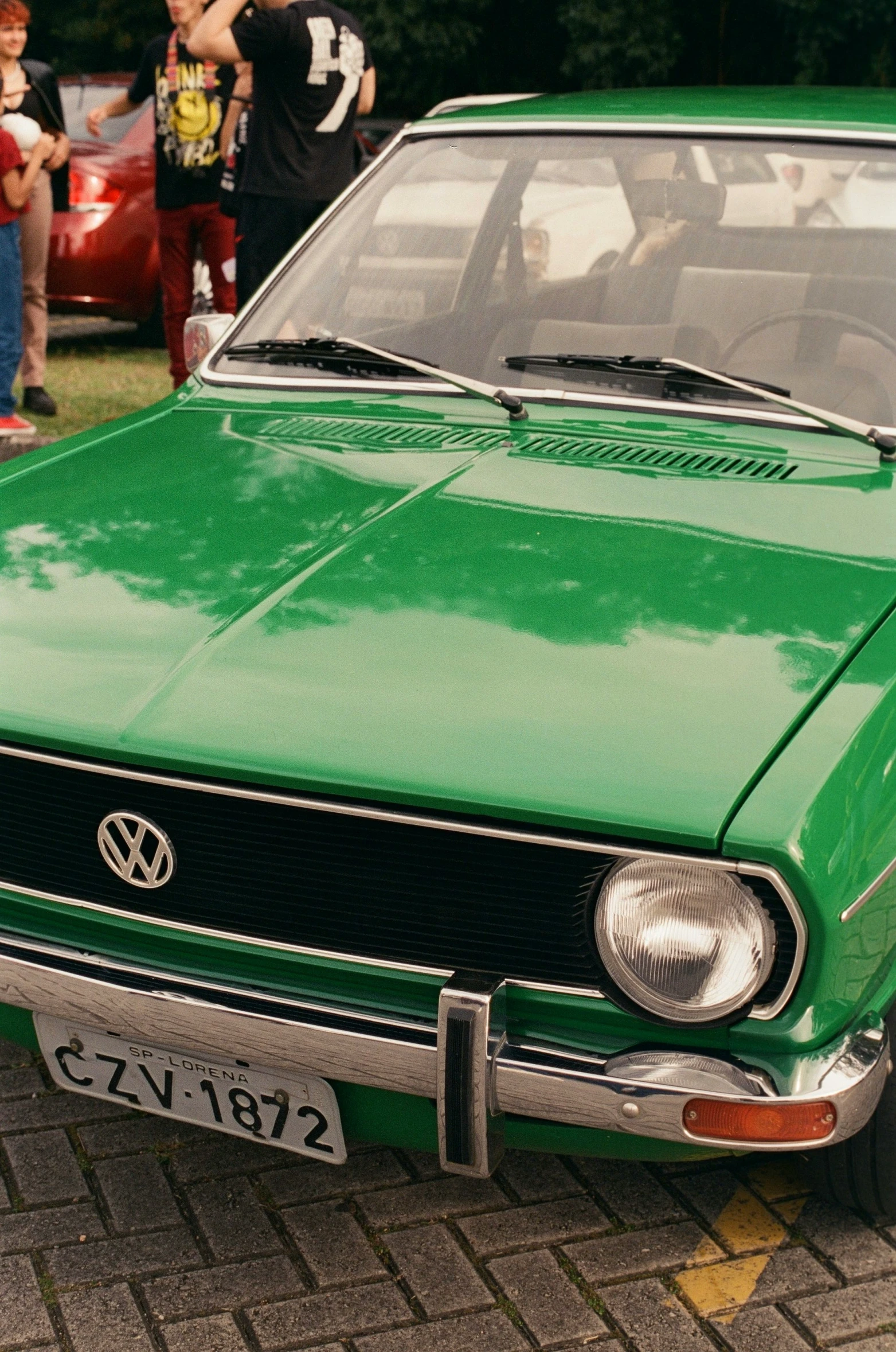 a green car with two people taking pos