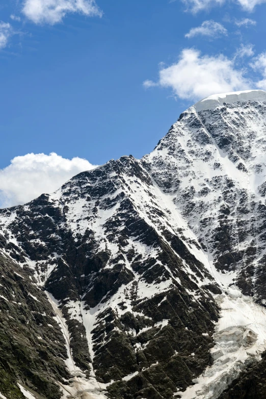 a group of snow capped mountains are seen with a cloud filled sky