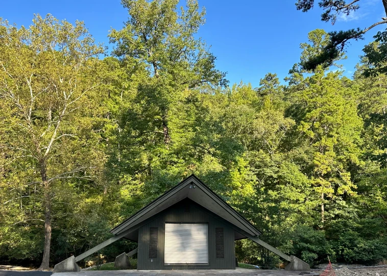 the cabin is in front of the woods near trees