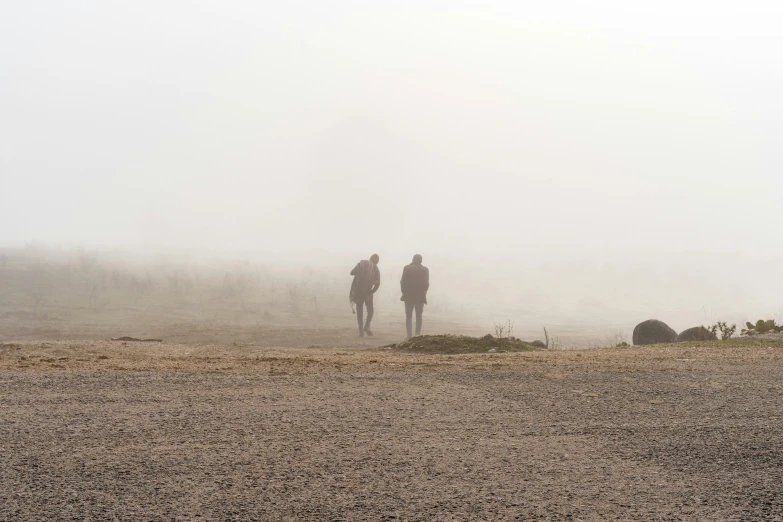 two people walking through a field on horseback