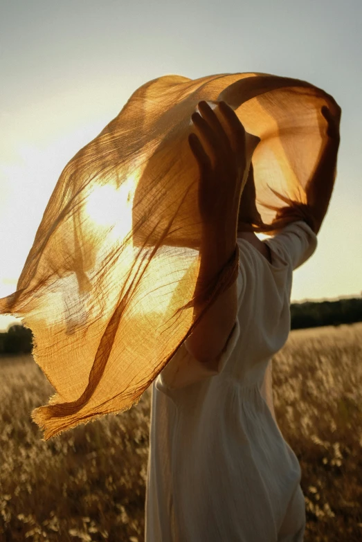 a woman holds a large yellow object in a wheat field