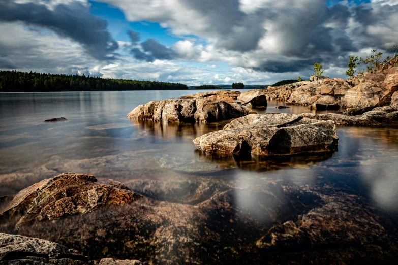 the rocks in the water are under a cloudy sky