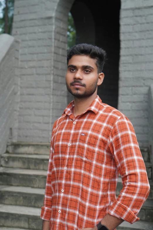 a man posing on steps in an orange shirt