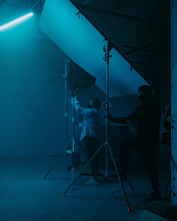 a man standing in a blue room behind a tripod