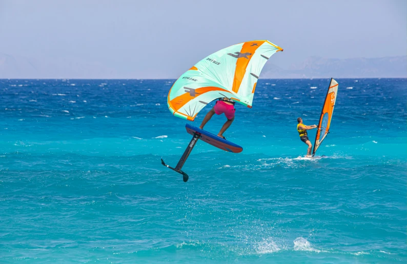 two people windsurfing in blue water on the ocean