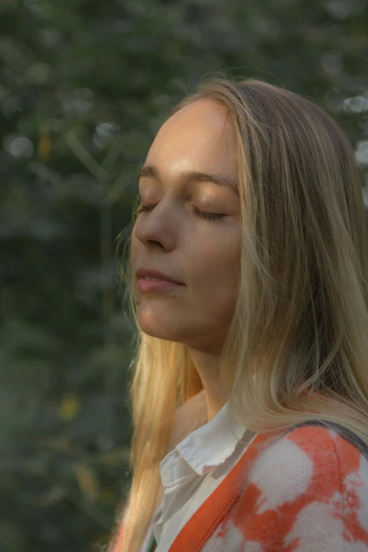 a woman with long blonde hair is posing in the forest