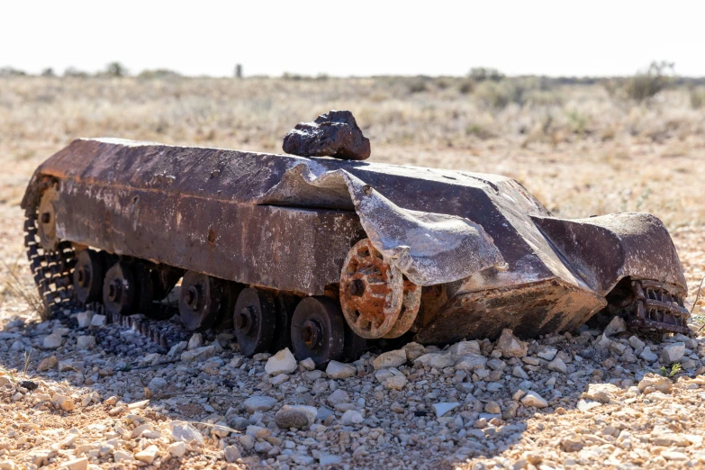 a small train laying in a field next to rocks