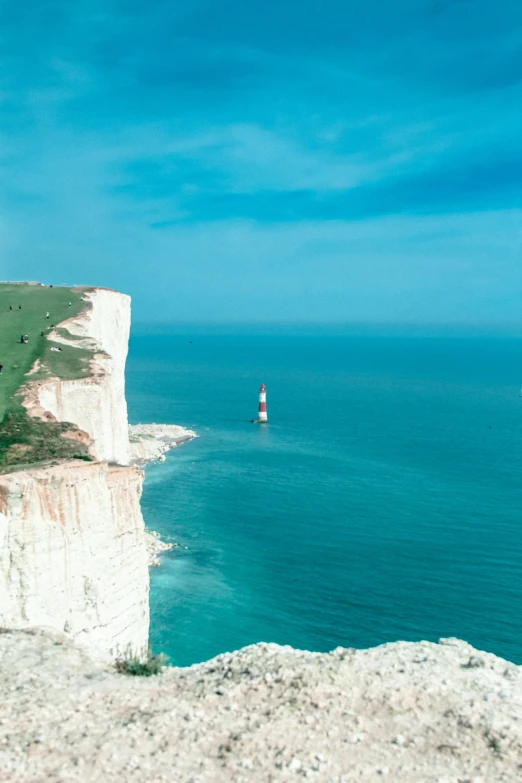 a beach with the cliffs and lighthouse in the distance