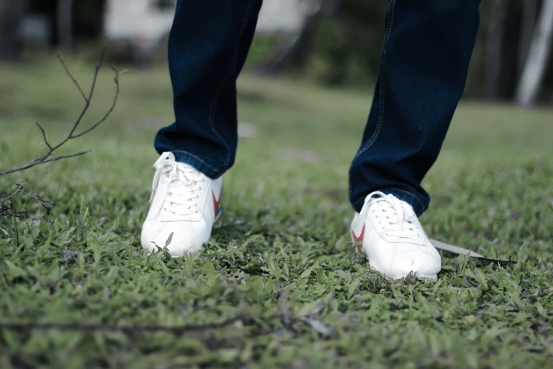 a person wearing white shoes in a field of grass