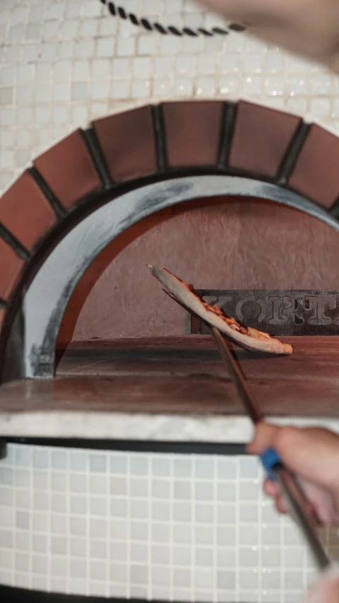 a pizza oven with someone holding up a pizza paddle