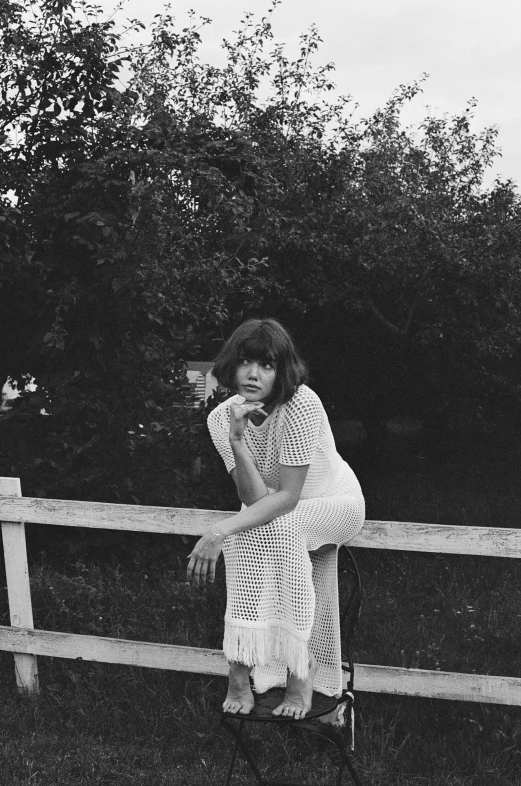 woman sitting on a wooden fence looking out over the trees