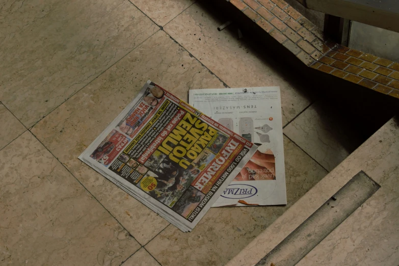 a newspaper laying on the floor with some newspaper nearby