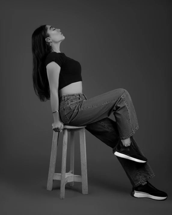 a woman in black shirt sitting on top of a stool