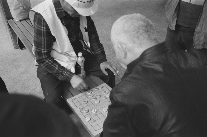 a man in a vest holding a monopoly board and standing next to a group of people