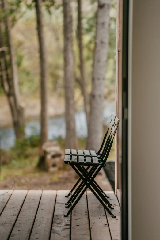 an open door to a deck has a small chair on it