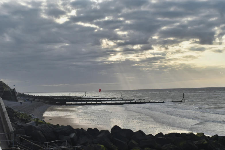 a body of water with clouds and a pier in the background