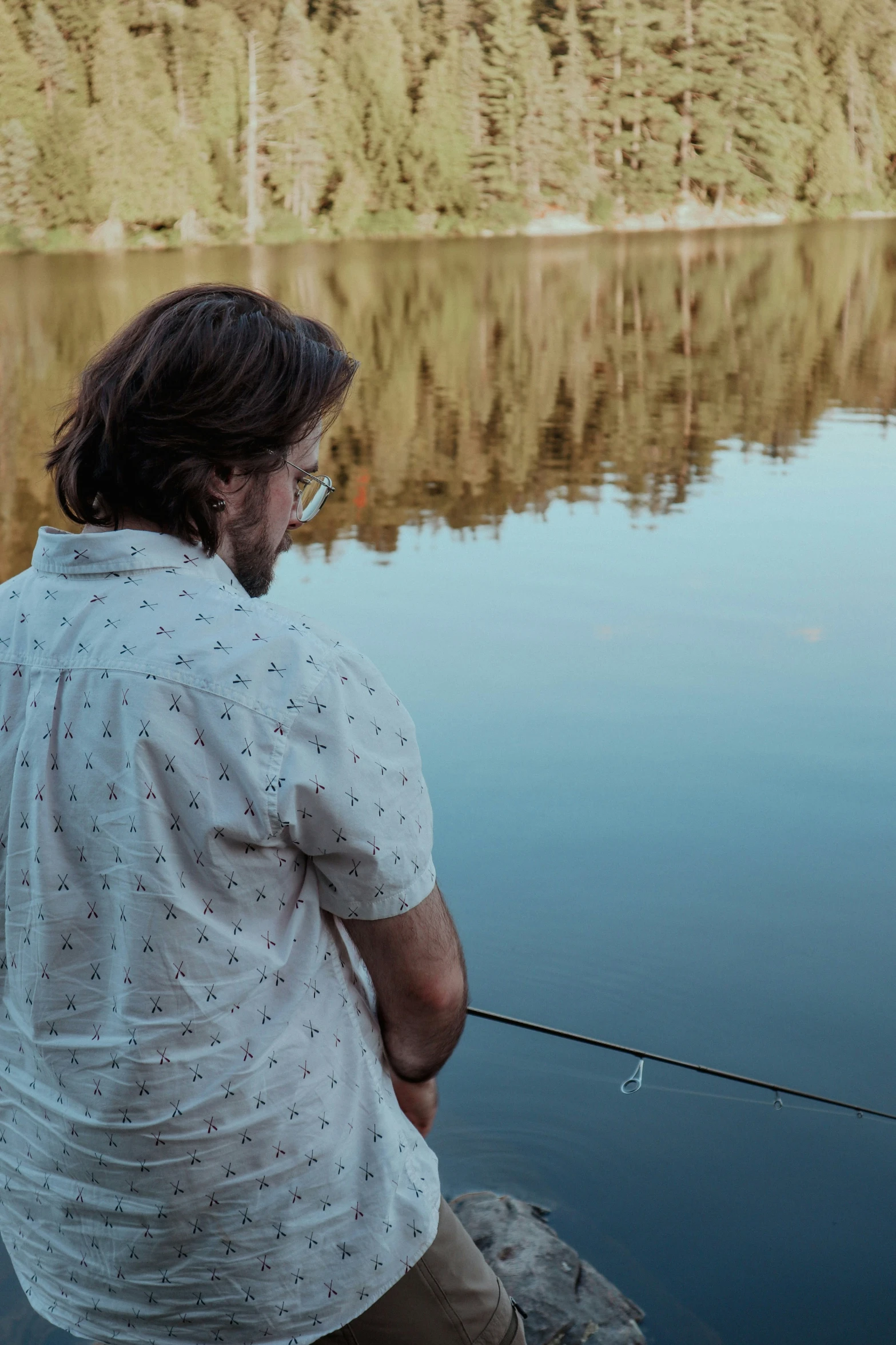 a man fishing on a river with water in the background