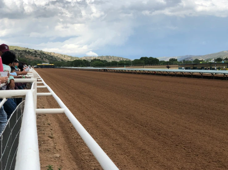 people in the stands looking at the horse race track