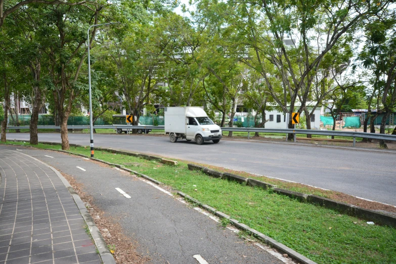 a van is driving down the street near the grass