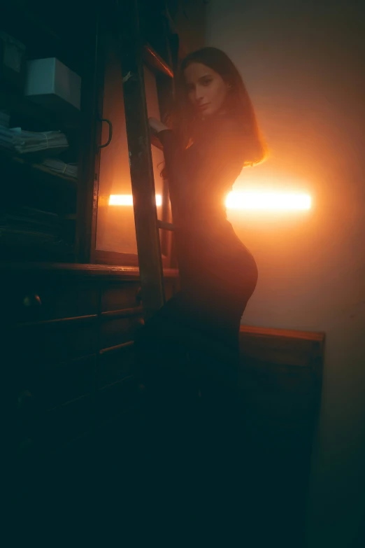 a woman is standing near a ladder in the dark