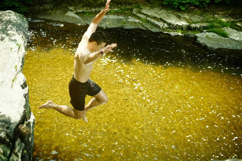 a man jumping from a cliff into the water