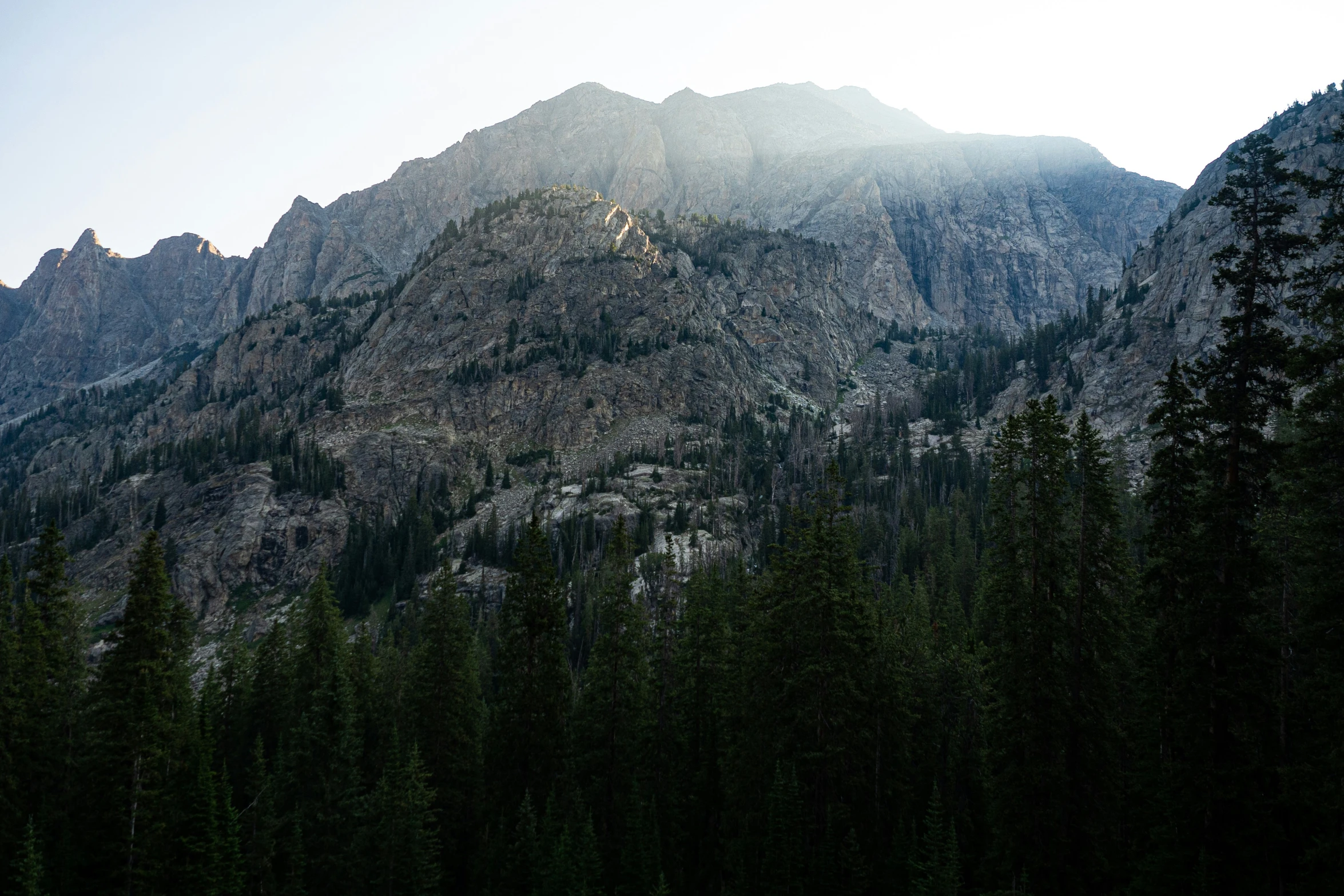 the sun is shining on some mountain peaks