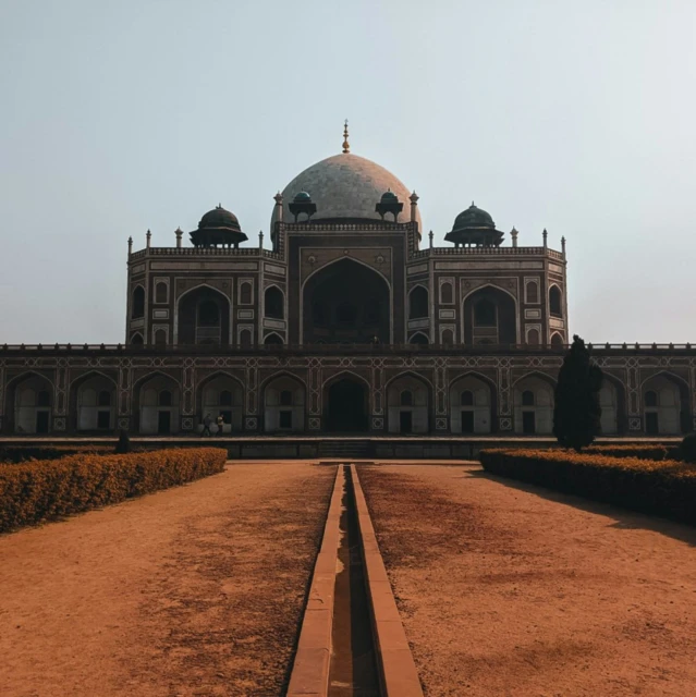 a tall building with two domes and a pathway