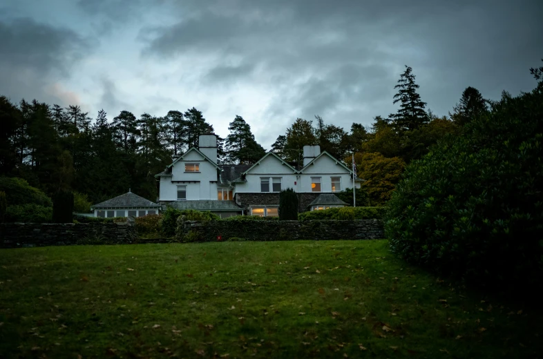 a large house in a lush green field with trees in the background