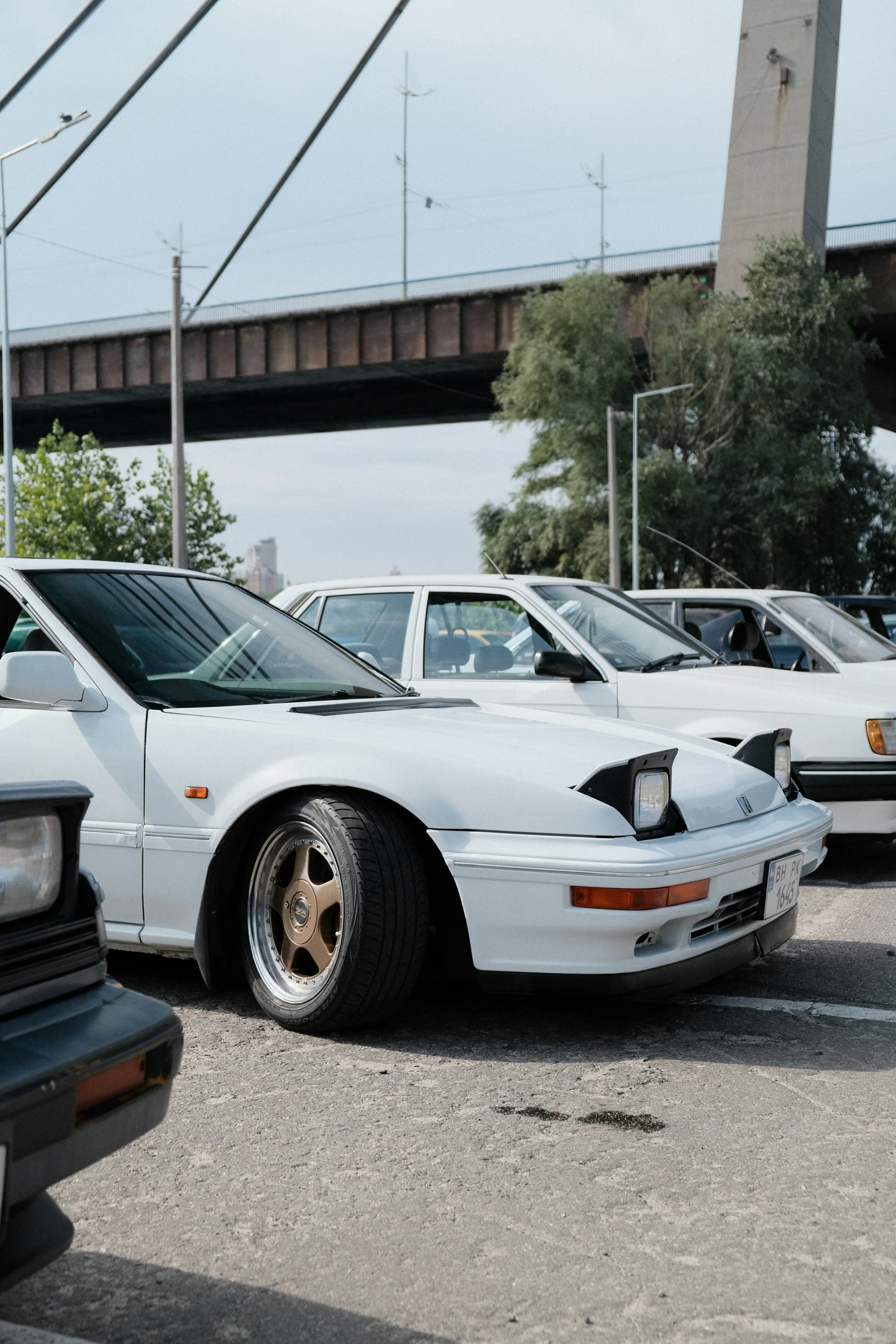 white cars are parked with a bridge in the background