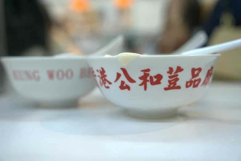 two porcelain bowls with chinese writing and spoons