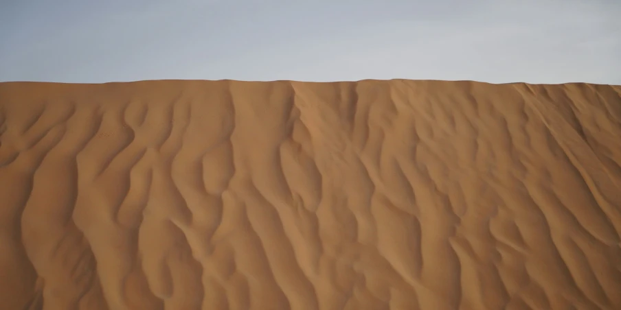 a very high sand dune with a person surfing on it