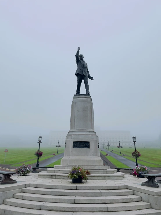 a statue on top of a set of stone steps in front of a large grassy field