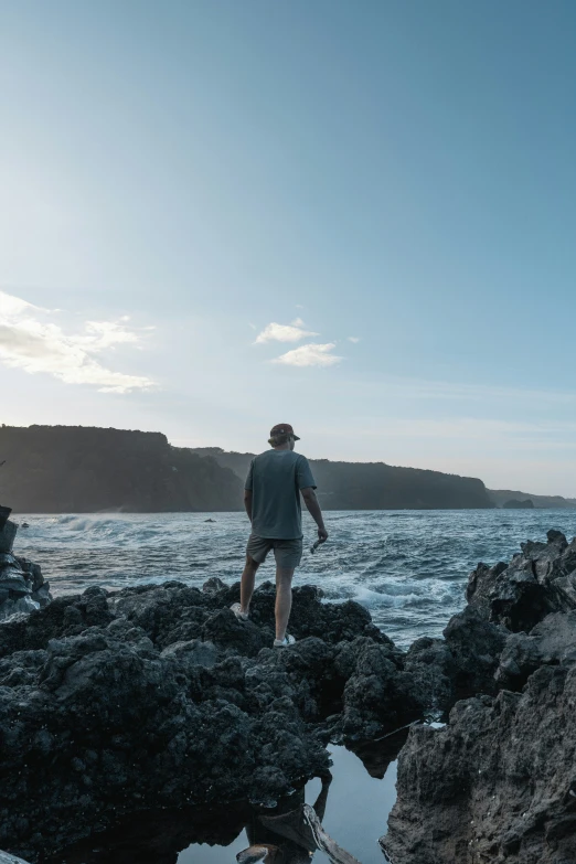 a man standing on rocks by the water