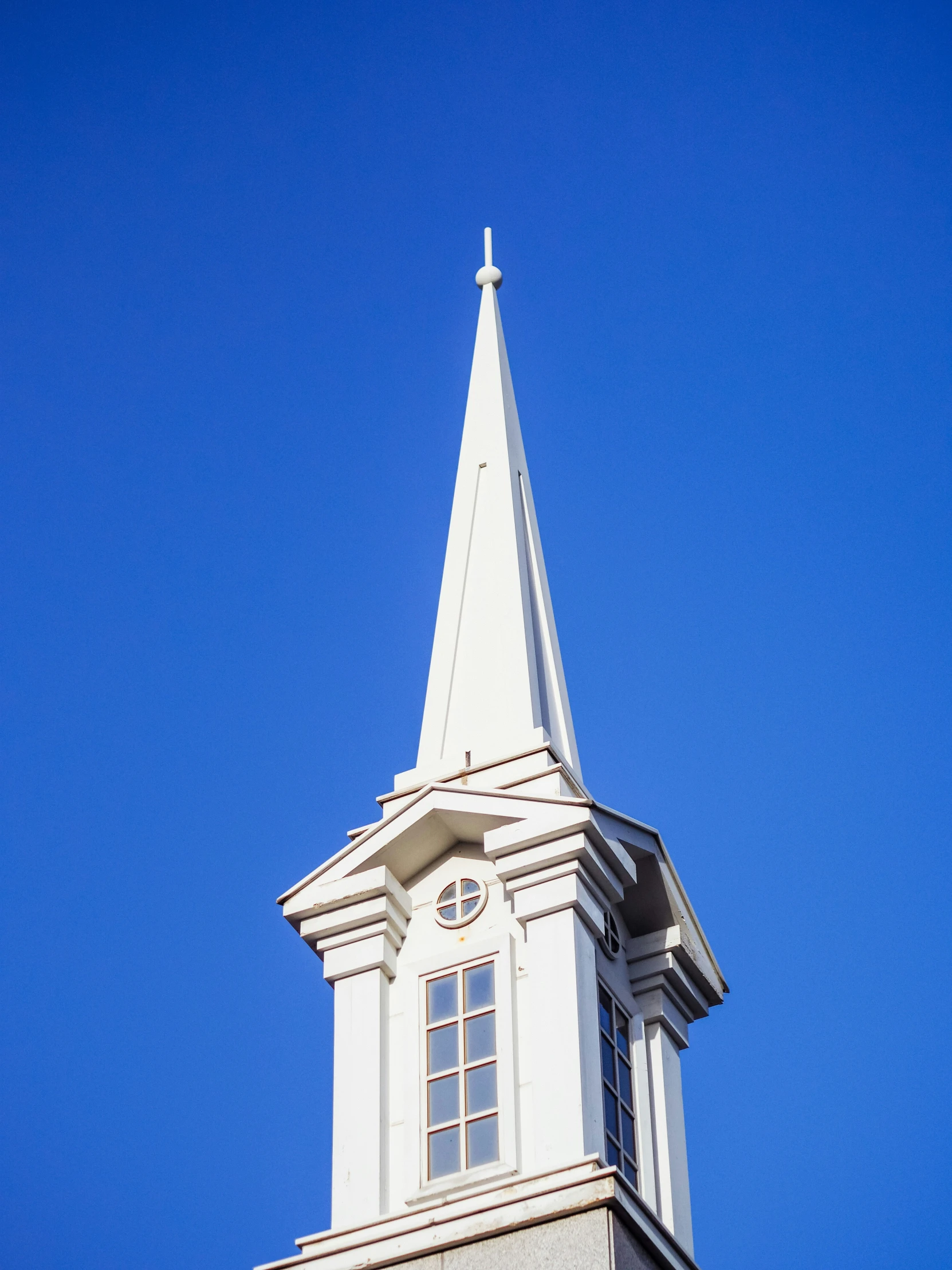 a tall white steeple against a bright blue sky