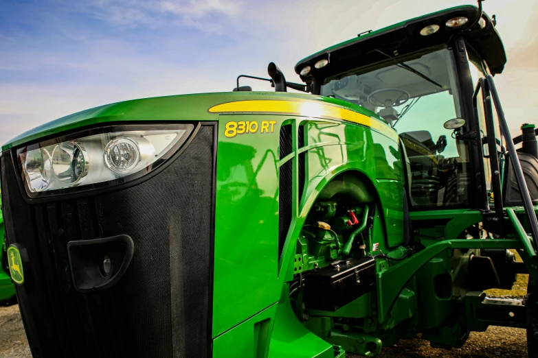 the front end of a green tractor parked in the grass