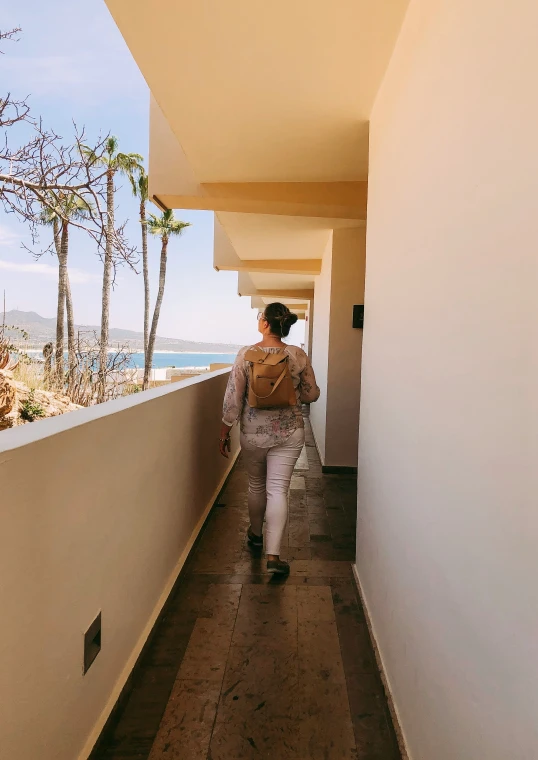 a woman with a backpack walking down a long walkway