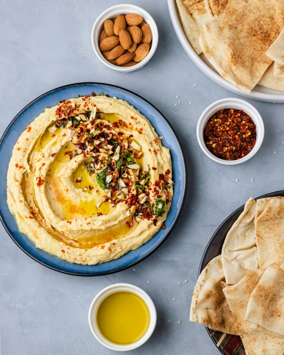 a plate of hummus and pita bread with sauce, mustard, nuts, and honey