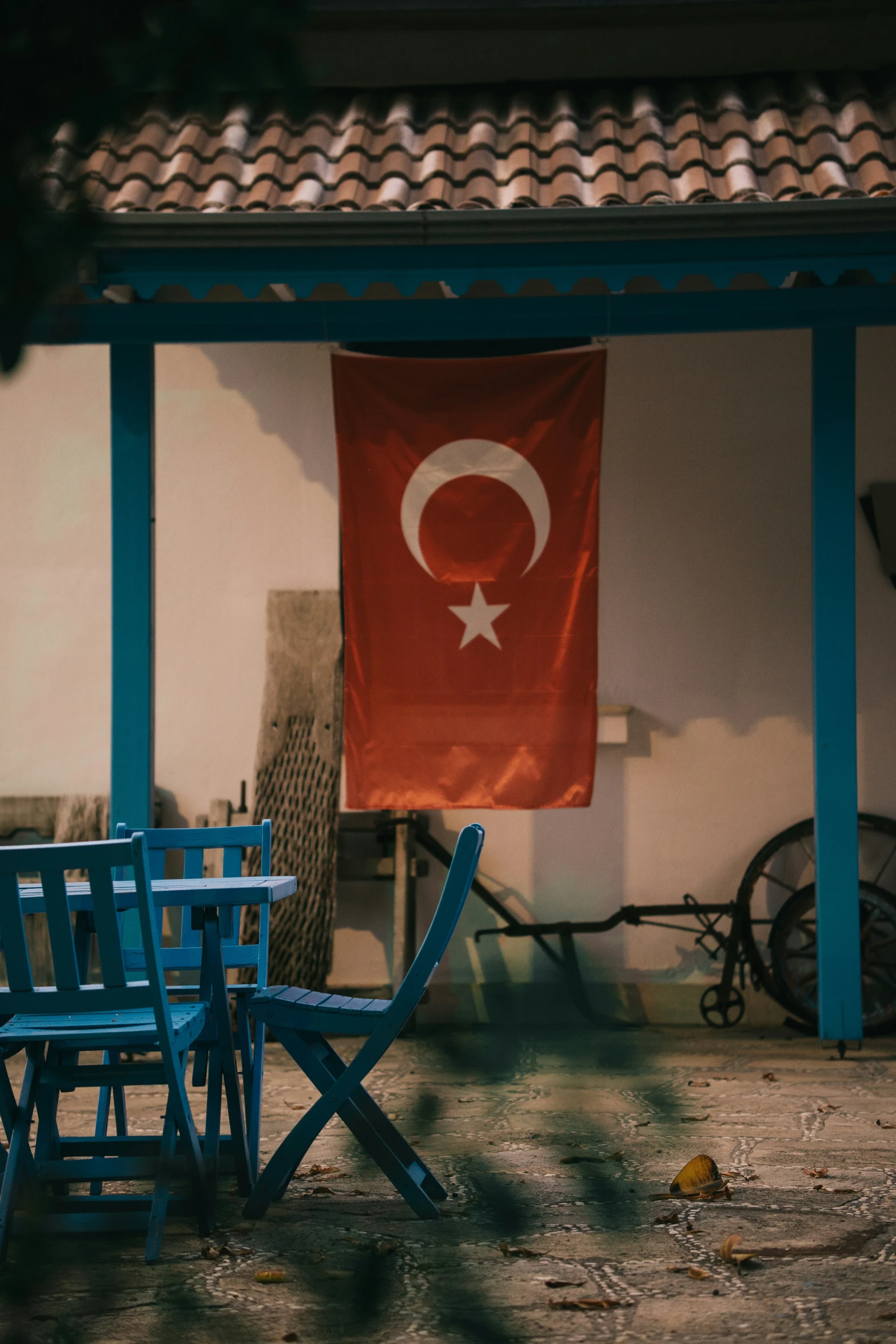 a turkish flag and three blue chairs sit in front of a building